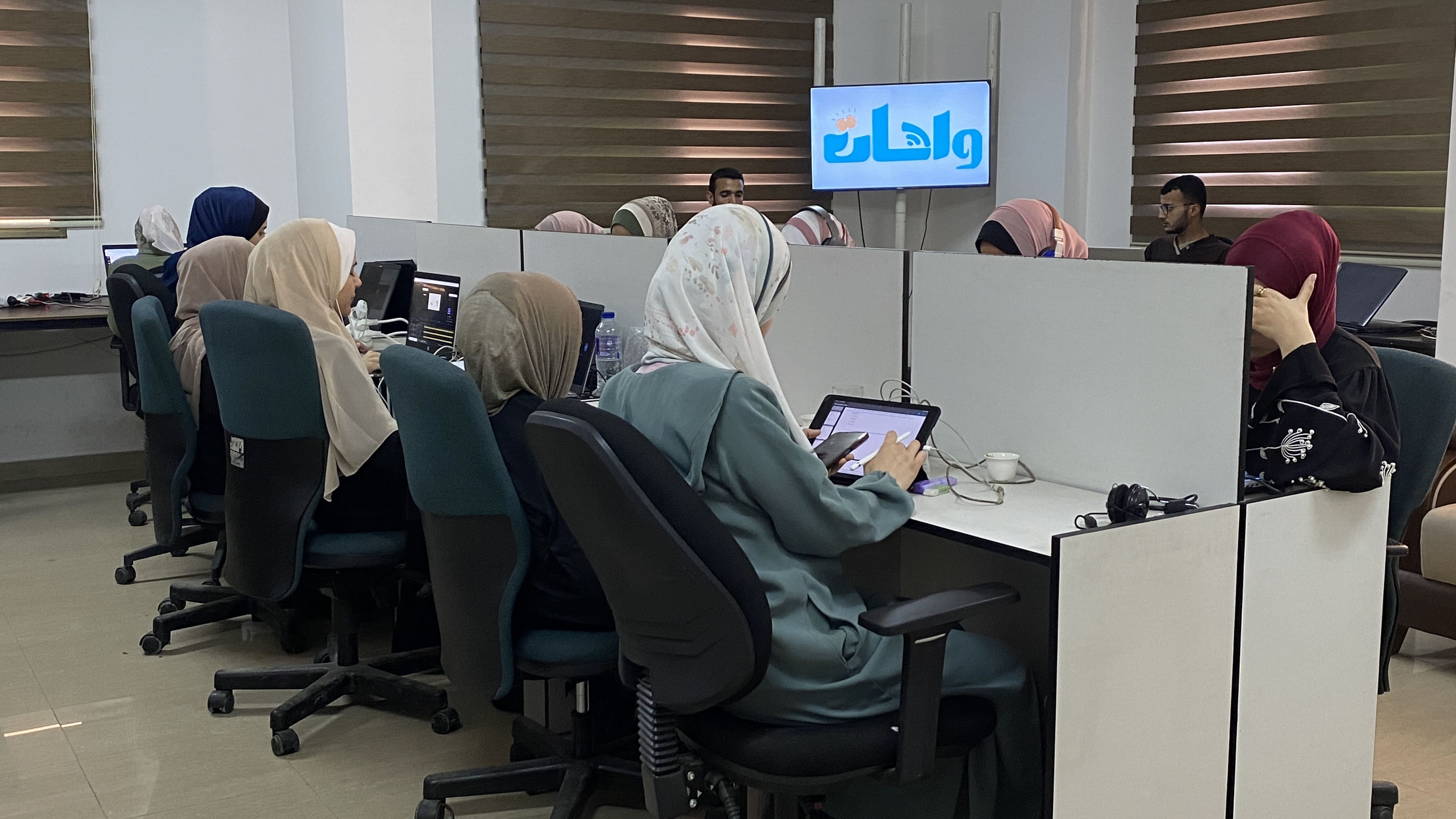 طالبات يعملن في مكتب حديث مع شعار واحات